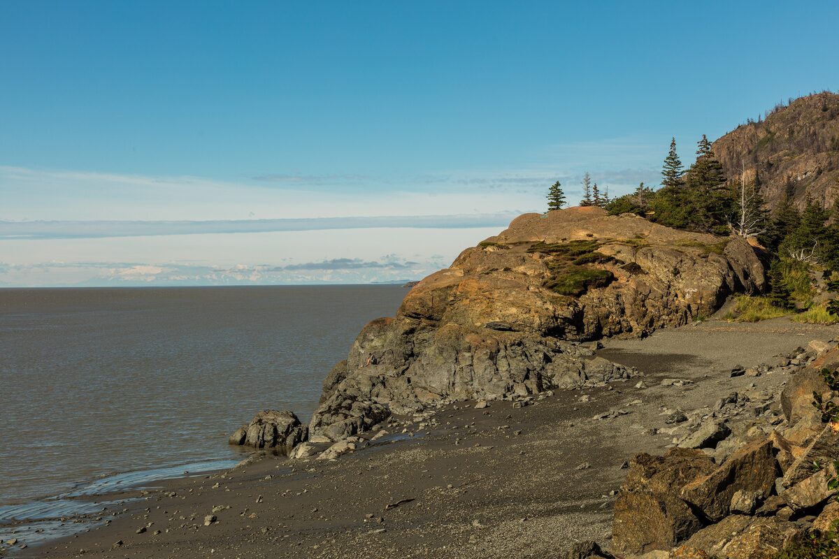 A rocky headland at Beluga Point above the Turnagain Arm mudflats on a clear summer day