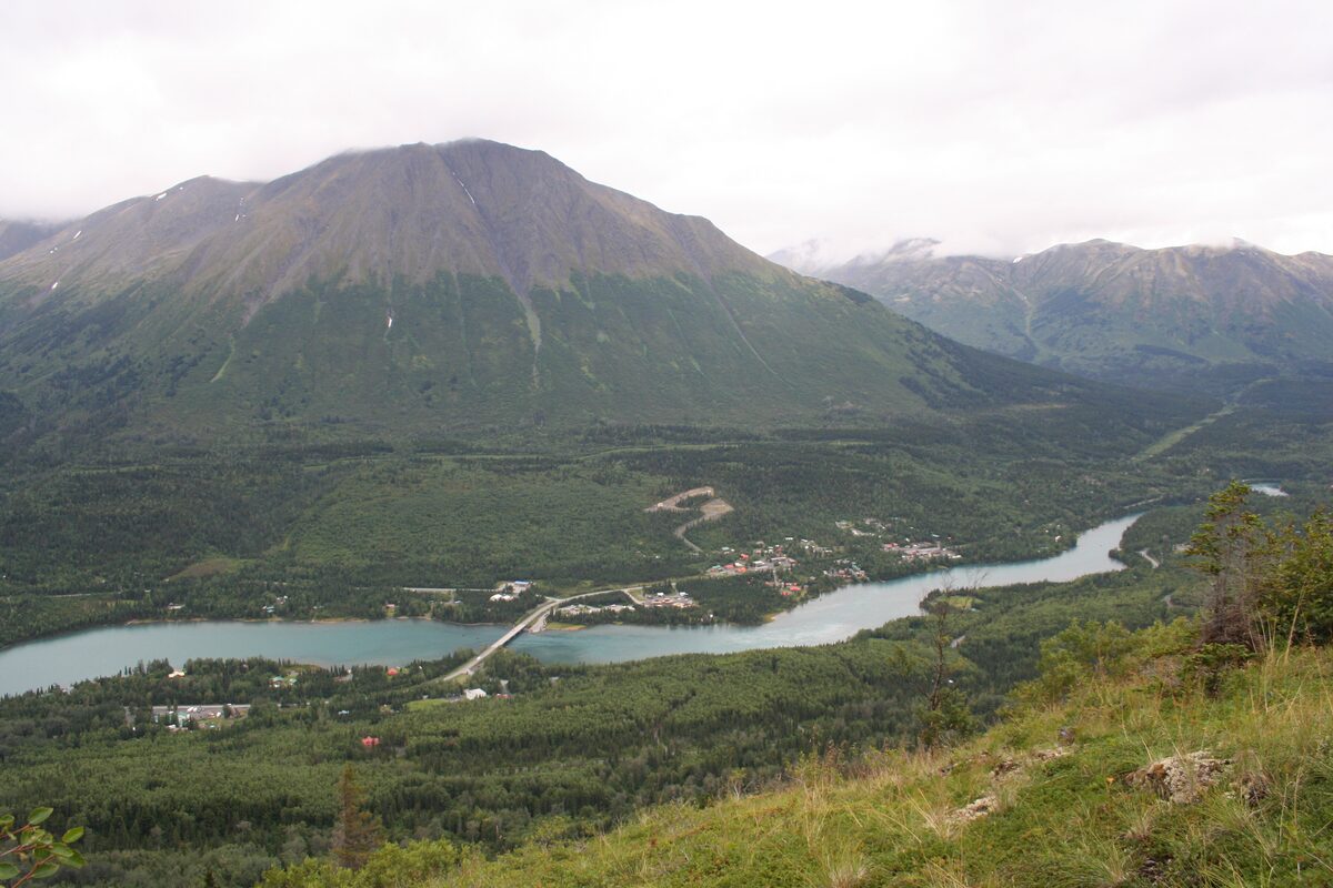 The village of Cooper Landing and the Kenai River below a broad green mountain