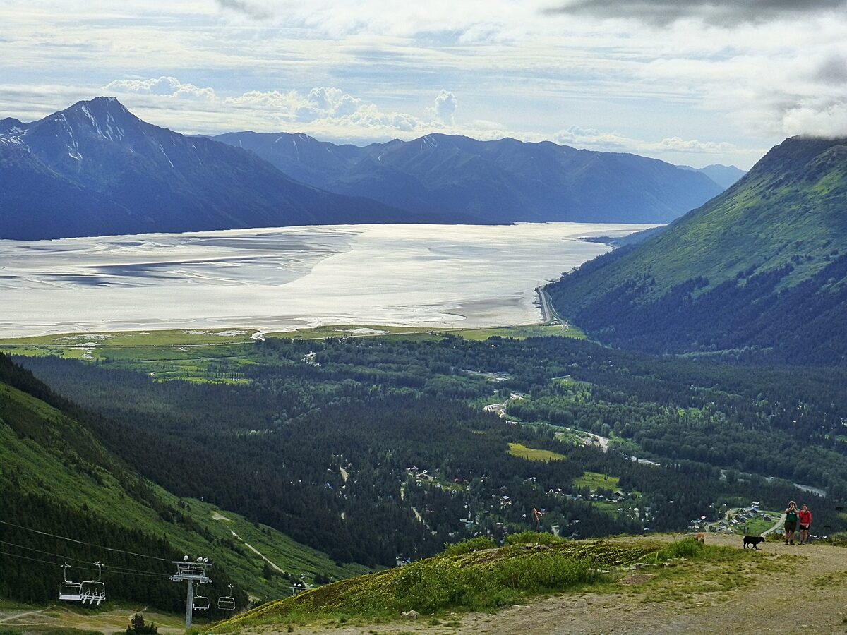 The Girdwood valley and the silty flats of Turnagain Arm seen from the mountain above town, with a ski chairlift in the corner