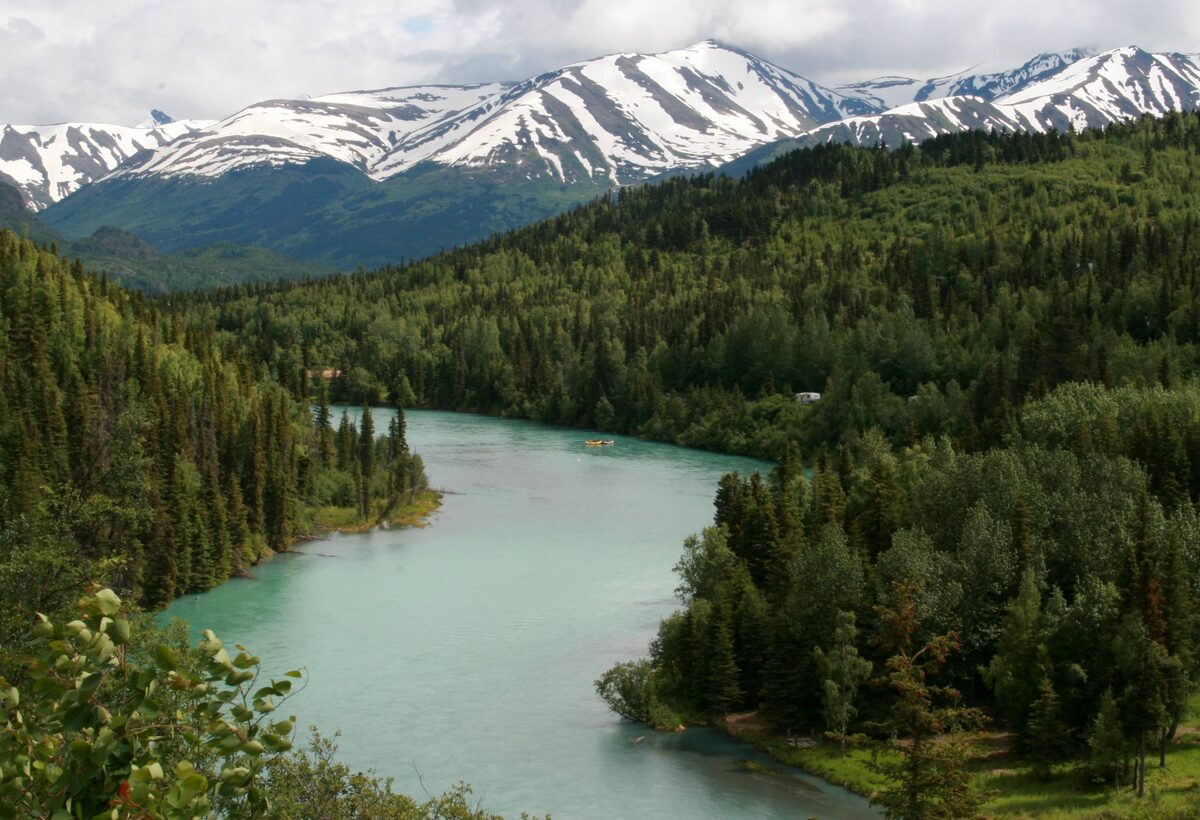 The turquoise Kenai River bending through spruce forest below snow-streaked mountains