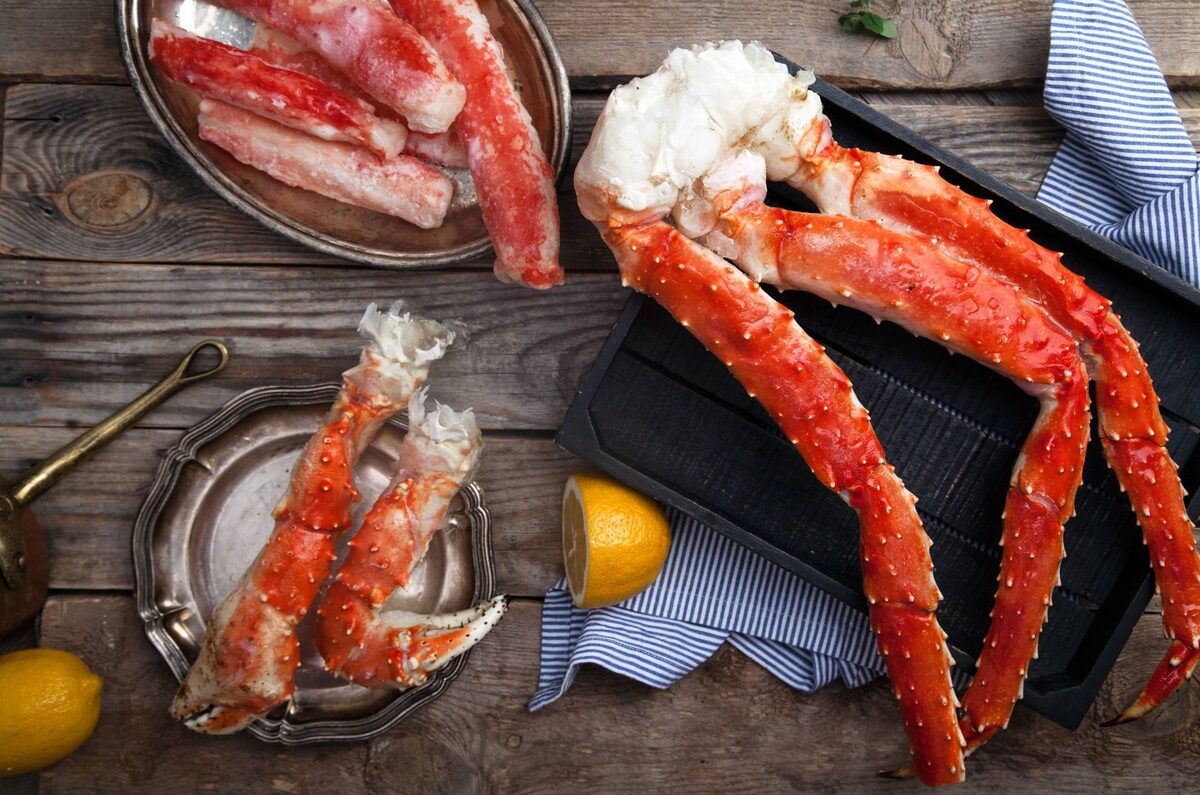 Cooked red king crab legs and claws on a wooden board with lemon