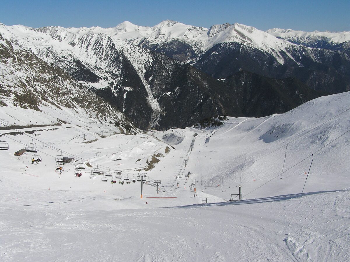Chairlifts and a drag lift crossing a snowy Arinsal basin, with high white peaks beyond, seen from the top of the run