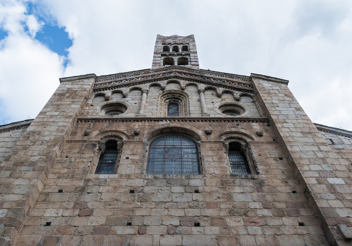 The Romanesque stone facade of the Cathedral of La Seu d'Urgell with round-arched windows and a tower above