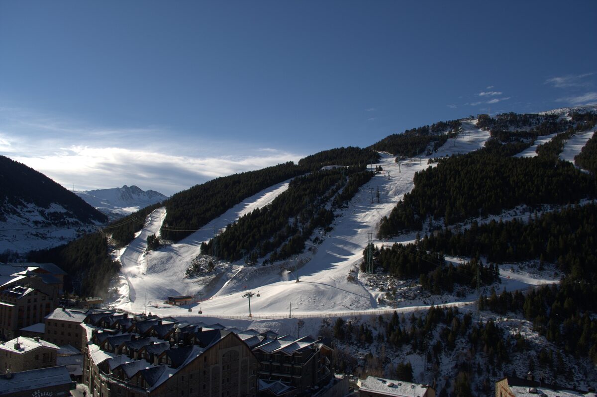 Soldeu village at the foot of its snowy ski slopes, with chalets and pistes climbing the hill above