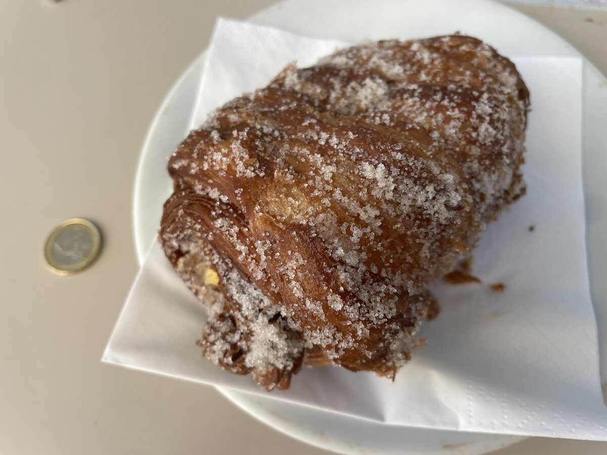 A xuixo, a fried spiral pastry rolled in sugar, on a paper napkin on a plate