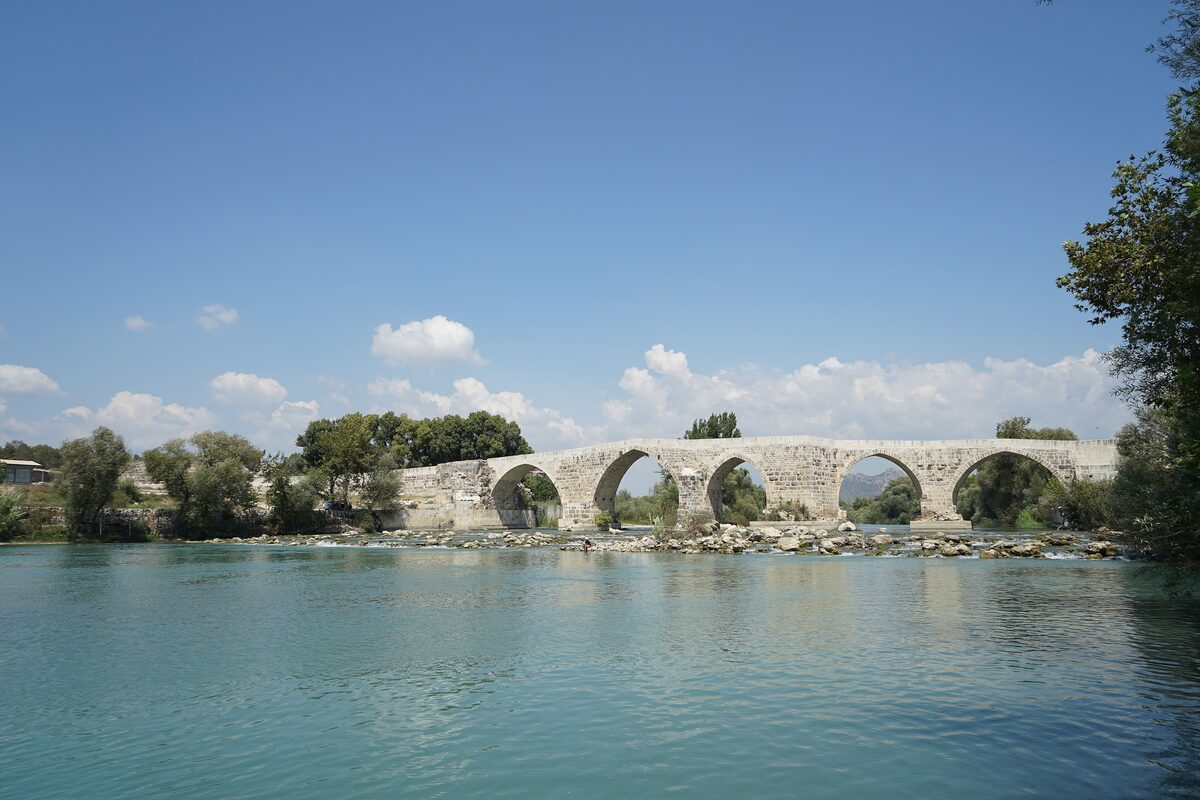 The multi-arched Eurymedon bridge across the wide, calm Köprüçay river near Aspendos