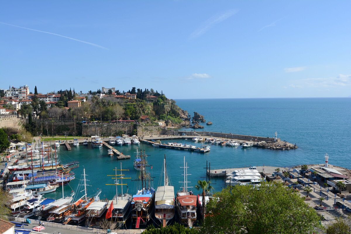 Antalya's old harbor from above, with rows of wooden gulets, the lighthouse on the breakwater and Kaleiçi on the headland