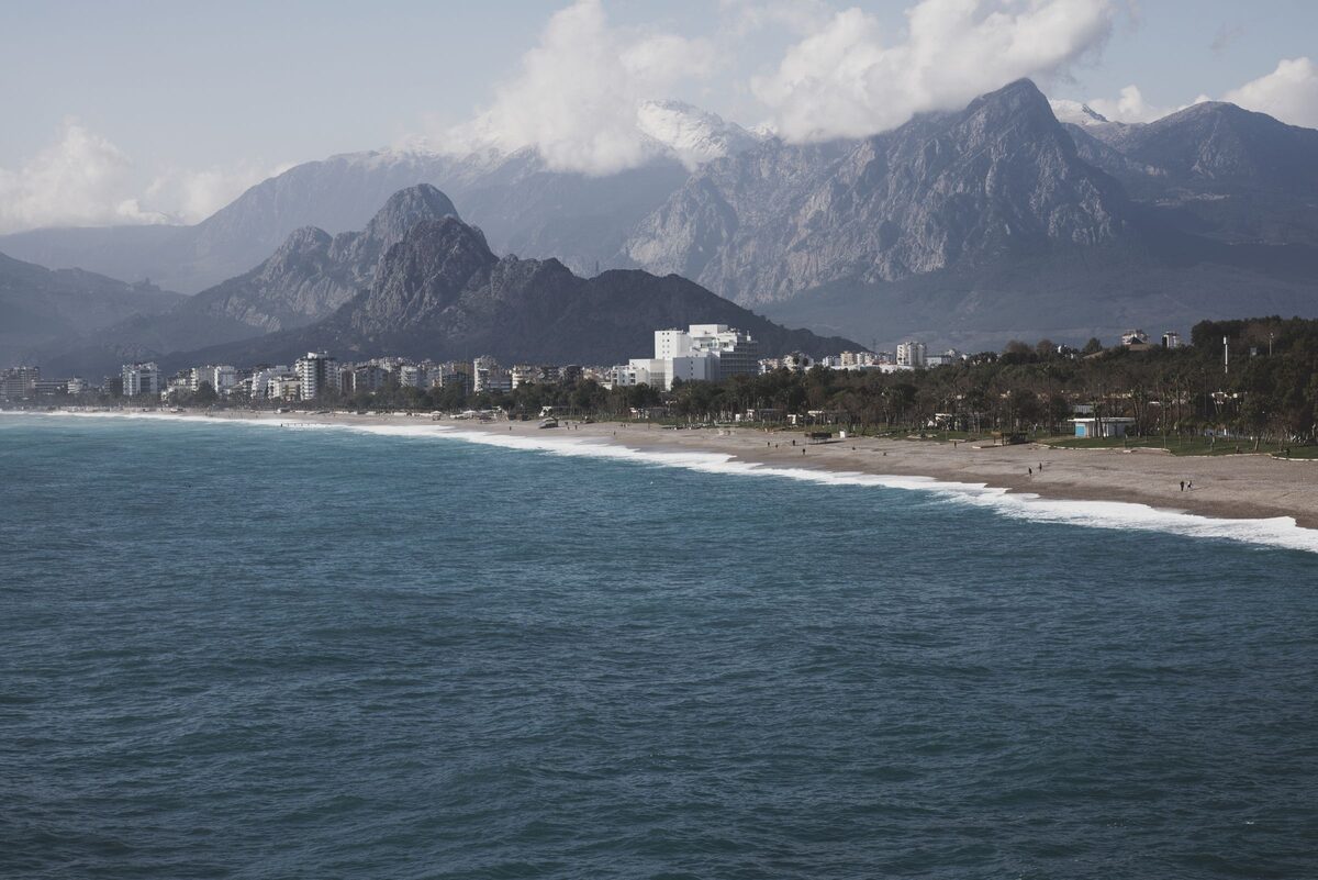 The long pebble beach of Konyaaltı with breaking surf and the jagged Beydağları mountains behind
