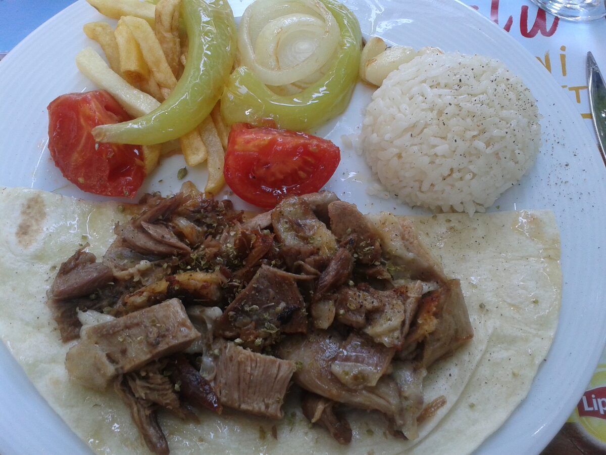 A plate of slow-roasted lamb tandır on flatbread with rice, grilled pepper and tomato