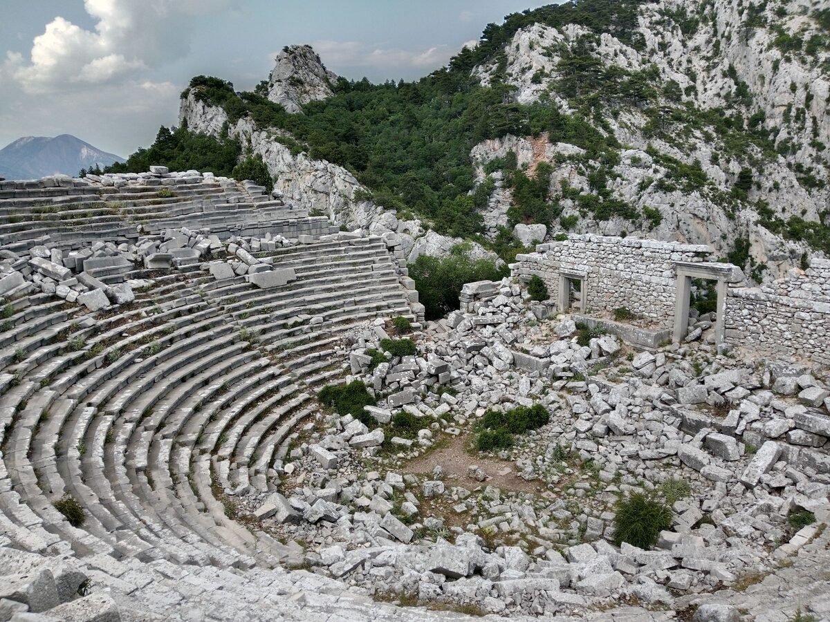 The theater of Termessos, tiers of grey stone seats and the ruined stage in a rocky mountain bowl