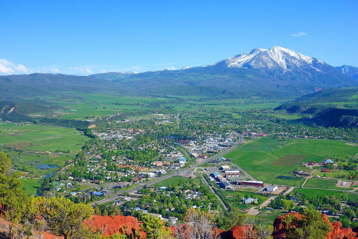 Carbondale seen from above, with green fields in the valley and the snow-capped Mount Sopris behind