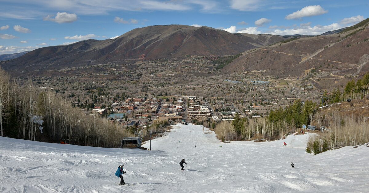 Skiers on the snowy runs of Aspen Mountain, with the town of Aspen in the valley below