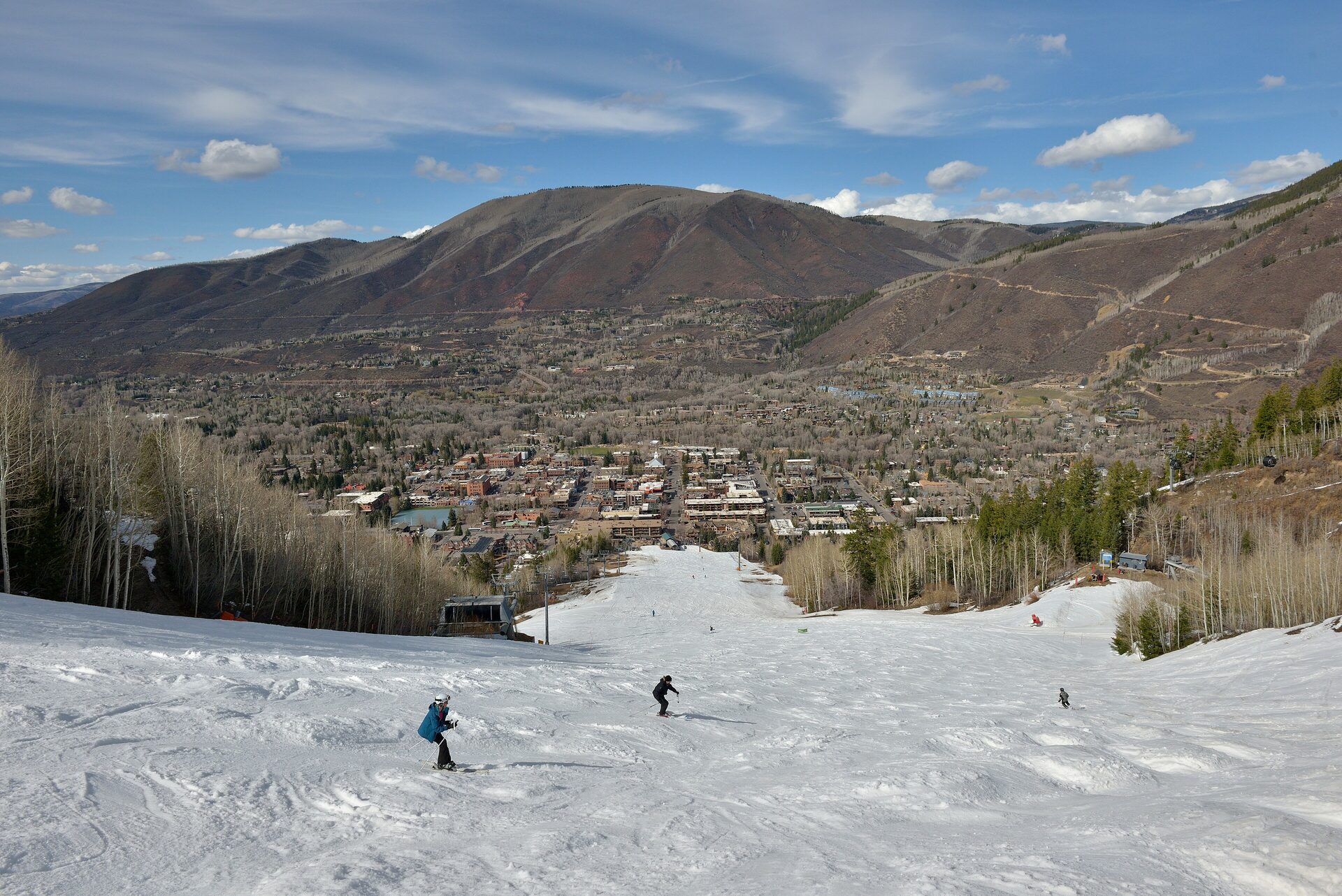 Skiers on the snowy runs of Aspen Mountain, with the town of Aspen in the valley below