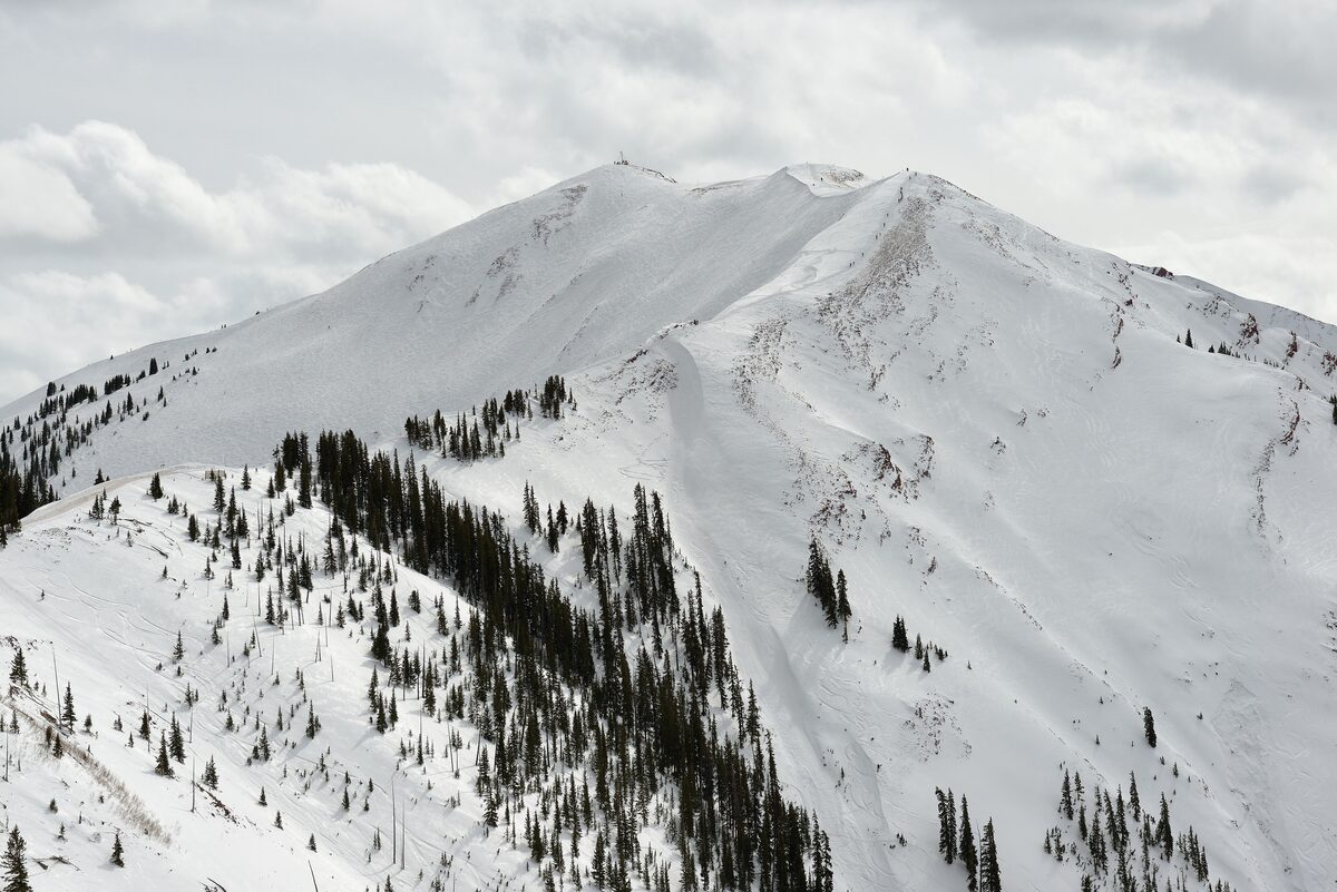 The snowy Highland Bowl on Aspen Highlands seen from Loge Peak, with fir trees on the flanks