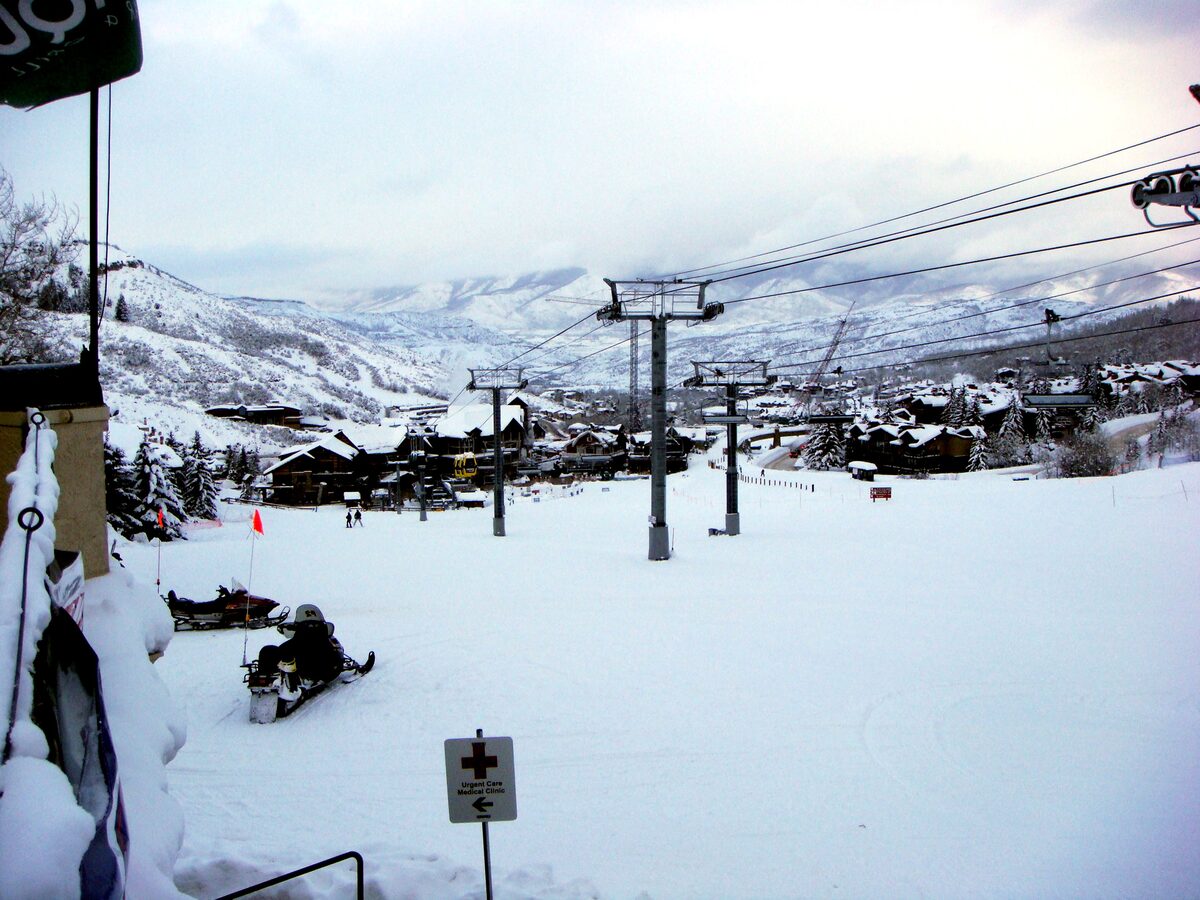 Snowmass Village in winter, with a chairlift, snow on the ground and the lodges below