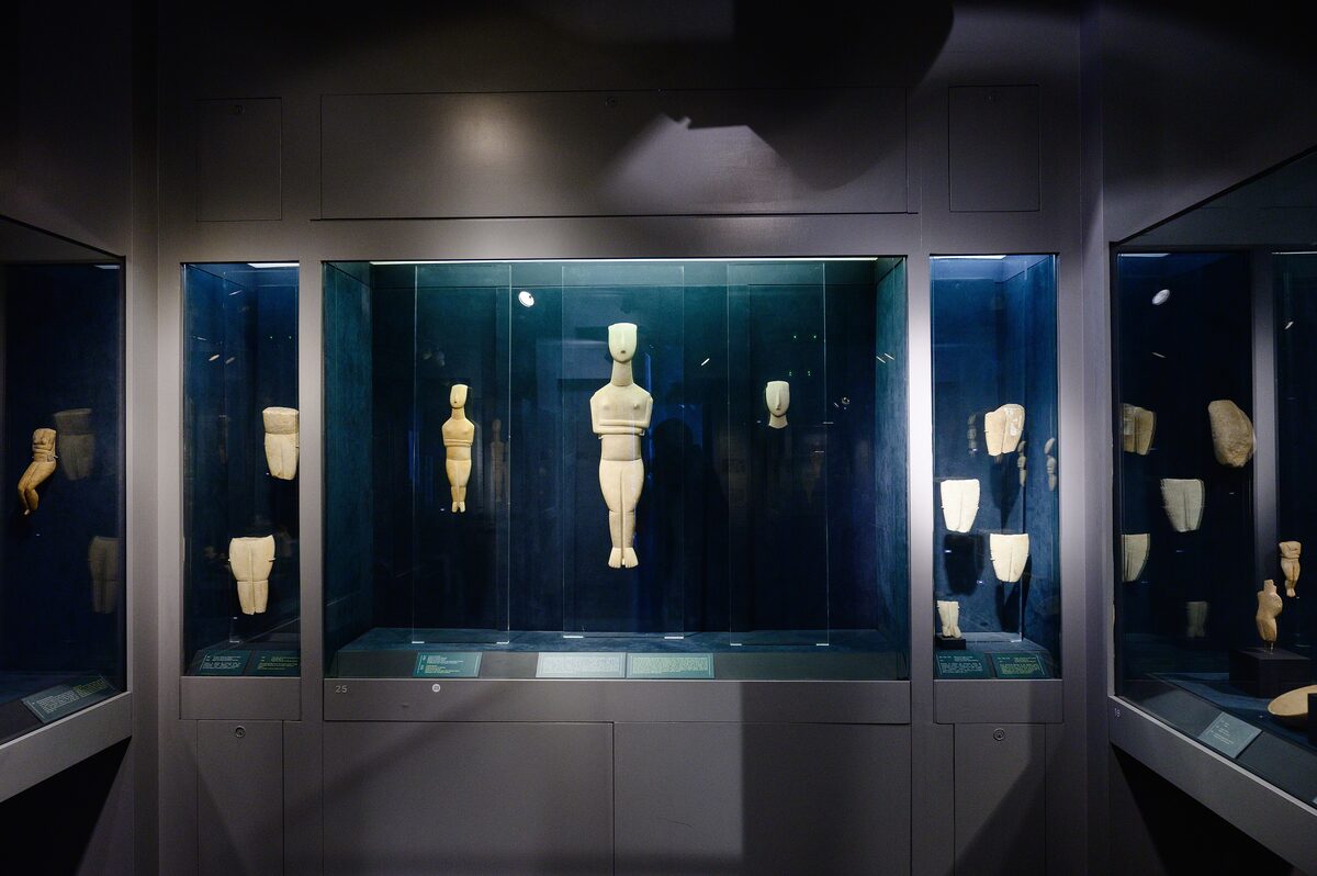 White marble Cycladic figurines in lit glass cases in a dark gallery of the Museum of Cycladic Art