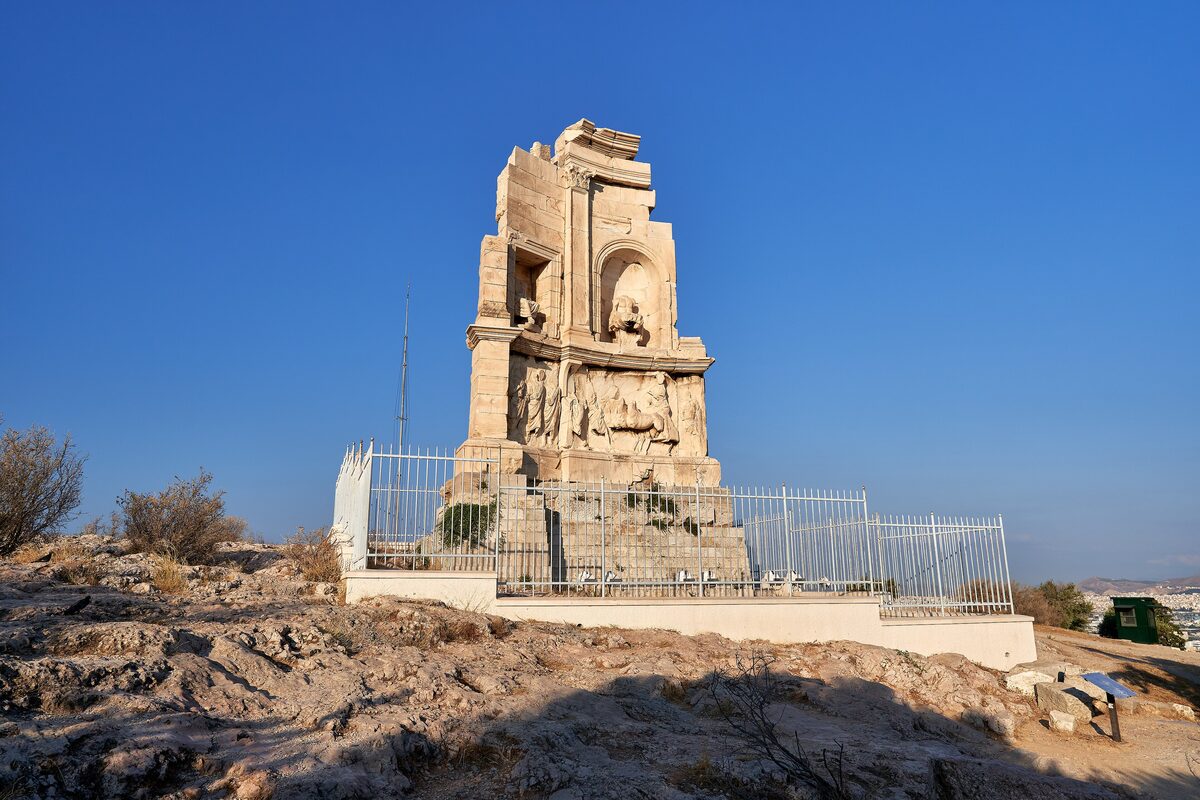 The marble Philopappos Monument on the rocky summit of Filopappou Hill in golden light