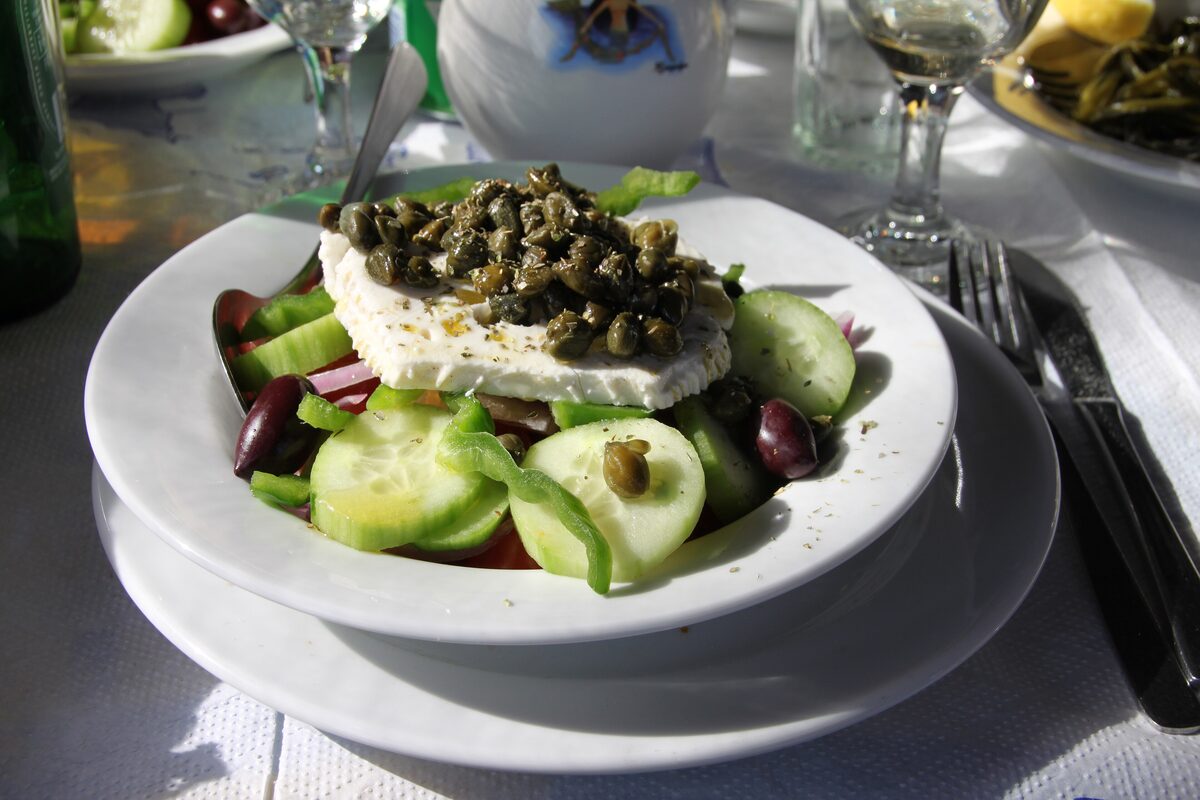 A horiatiki salad of cucumber, tomato, green pepper and olives topped with a slab of white cheese and capers