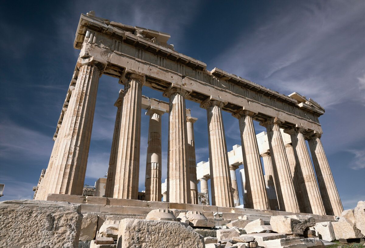 Low-angle view of the Parthenon's marble colonnade against a deep blue sky
