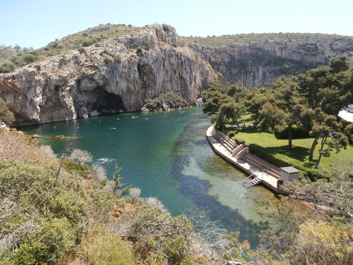 Lake Vouliagmeni from above, turquoise water under limestone cliffs with a bathing deck and pines