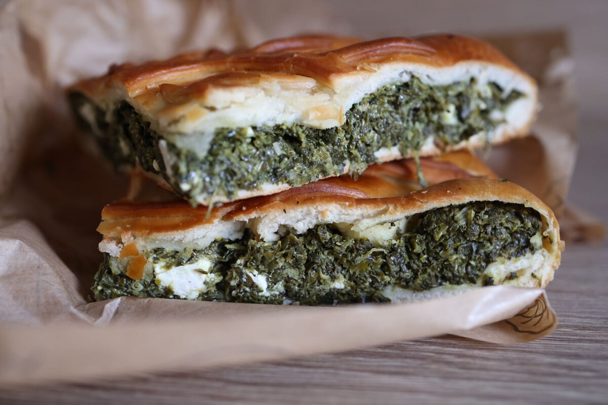 Two slices of spanakopita showing the spinach and cheese filling between flaky layers of phyllo