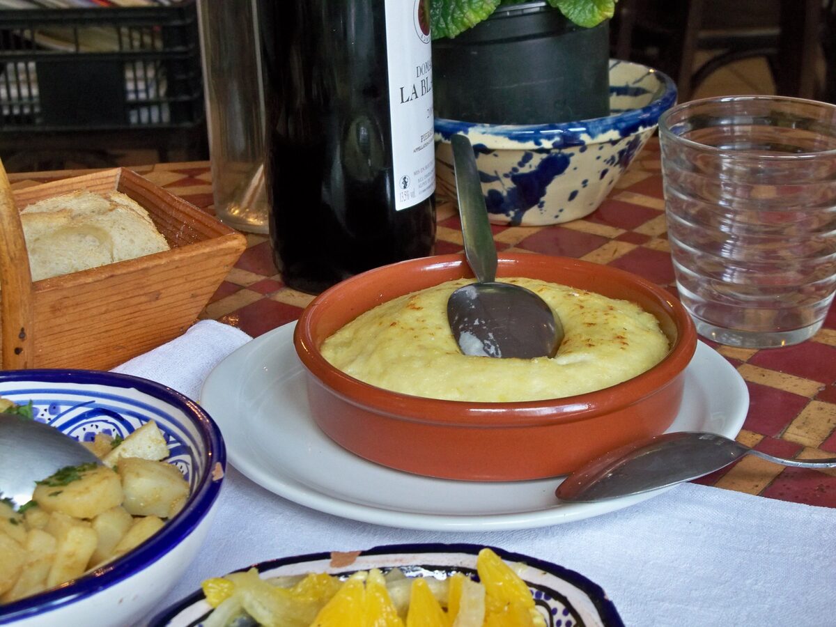 Brandade, a creamy salt cod and potato dish in an earthenware dish, served with bread and potato slices
