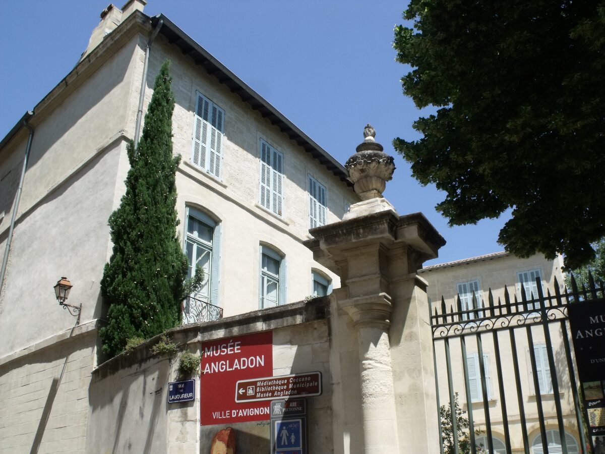 The gate and street sign of the Musée Angladon, in front of an 18th-century town house with a cypress tree