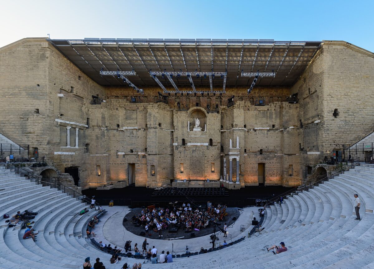 The high stage wall and tiered seats of the Roman theatre in Orange, with the stage set up for a performance