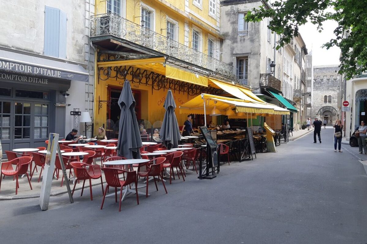 The yellow café terrace on the Place du Forum in Arles, with red chairs and closed parasols, the café Van Gogh painted