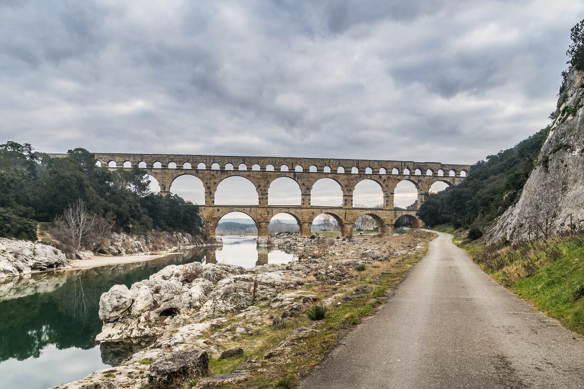 The three tiers of the Pont du Gard aqueduct over the Gardon river, with a narrow road along the bank