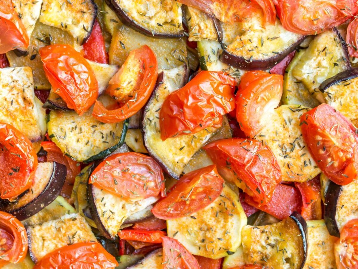 Close-up of ratatouille: roasted tomato halves, eggplant and zucchini slices with herbs