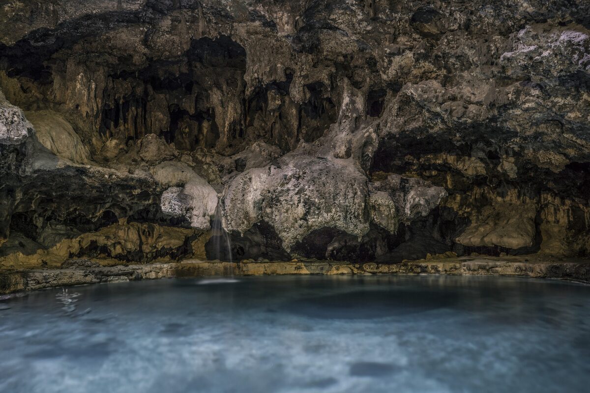 The steaming thermal pool inside the Cave and Basin cavern, with the rock ceiling and a trickle of water above it