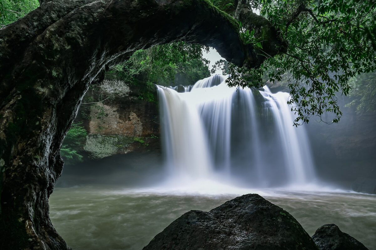 The Haew Suwat waterfall pouring over rocks beneath a tree arch in Khao Yai National Park