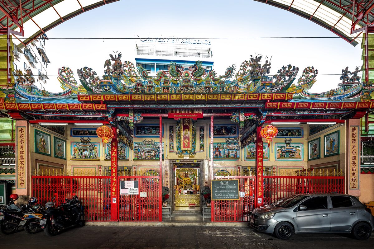 The red gate and dragon-carved roof of the Cho Su Kong shrine in Talat Noi