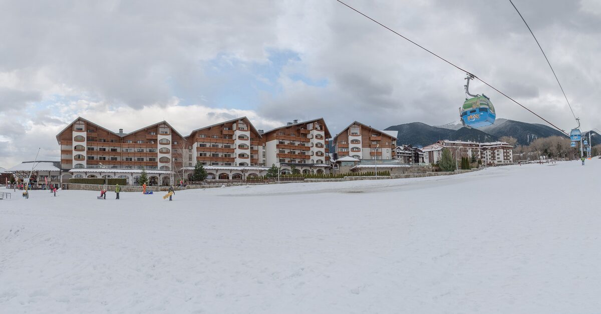 Hotel buildings and a gondola cabin above a wide snow-covered slope at Bansko