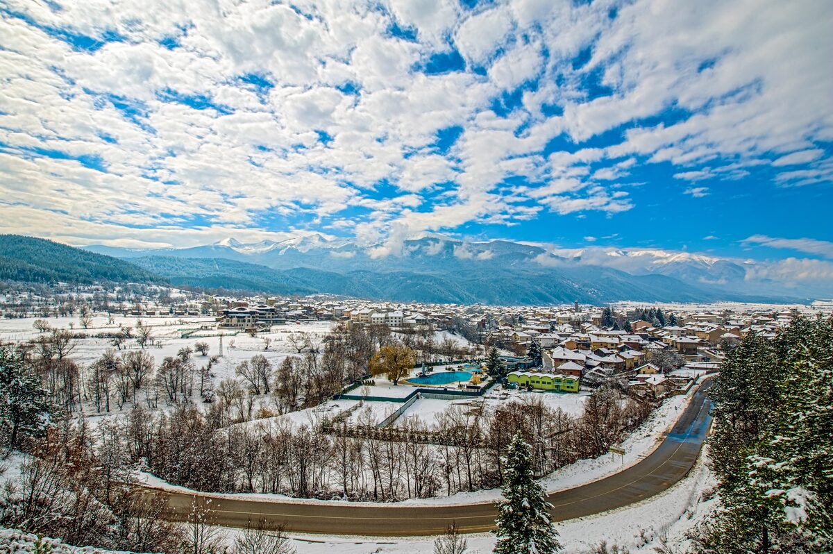 Dobrinishte in snow, seen from the hills above the village, with the roofs and roads below