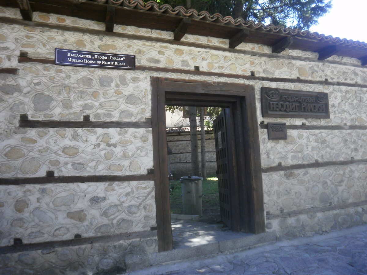 The stone gate and wooden door of the Neofit Rilski house museum in Bansko, with its plaque