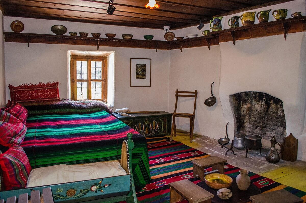 Inside the Nikola Vaptsarov house museum in Bansko: a painted bed, woven rugs and copper pots by the fireplace