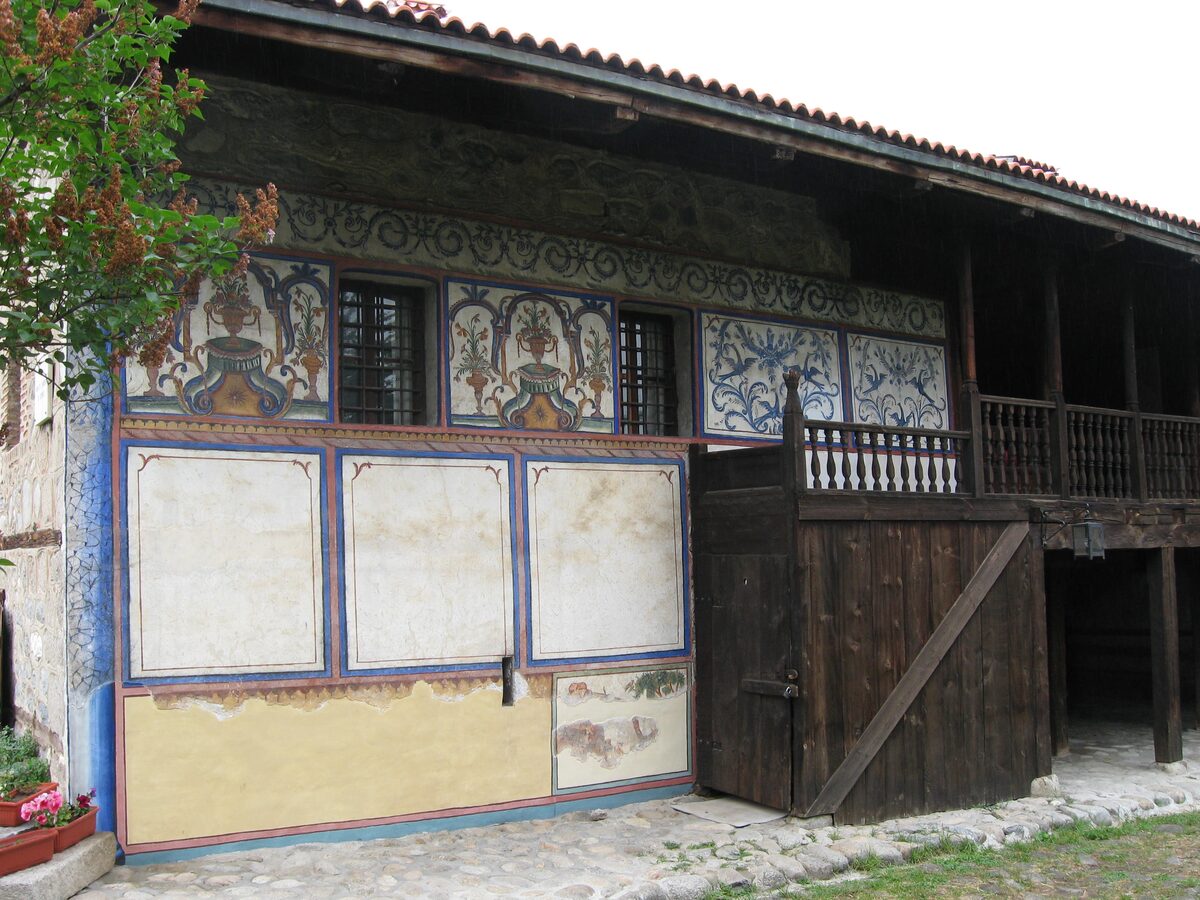 The painted upper facade and wooden gallery of Velyan's House around its courtyard in Bansko