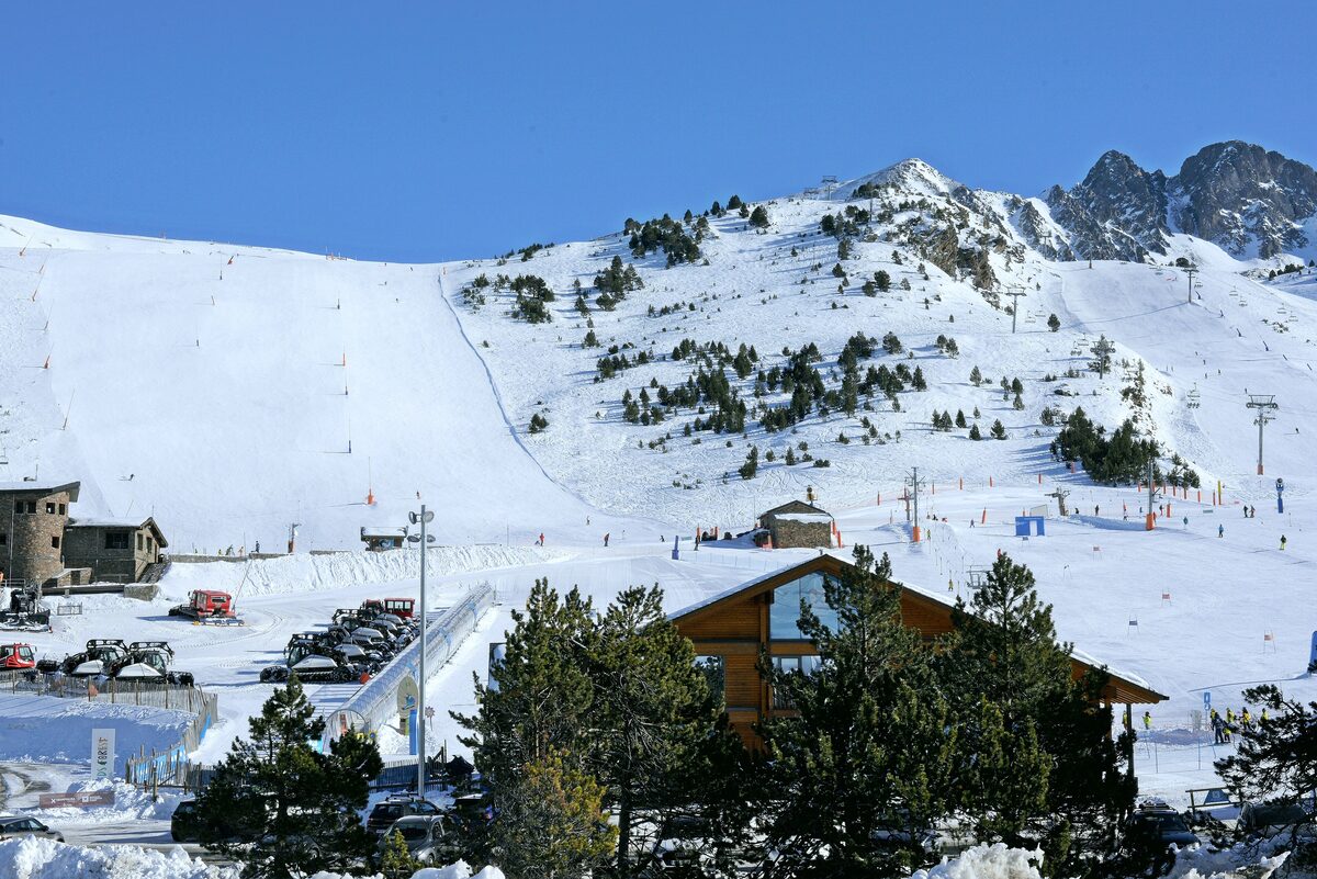 Groomed pistes, lifts and a wooden mountain restaurant in snow at Grandvalira in Andorra