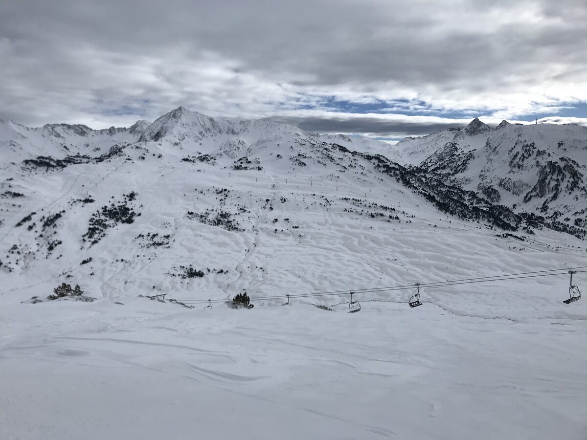 Open snowy mountain slopes with a chairlift line under a grey and blue sky at Baqueira-Beret