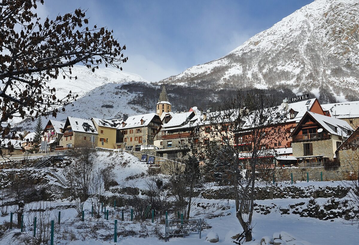 Salardú's old stone village in snow, with its church tower and the mountains behind