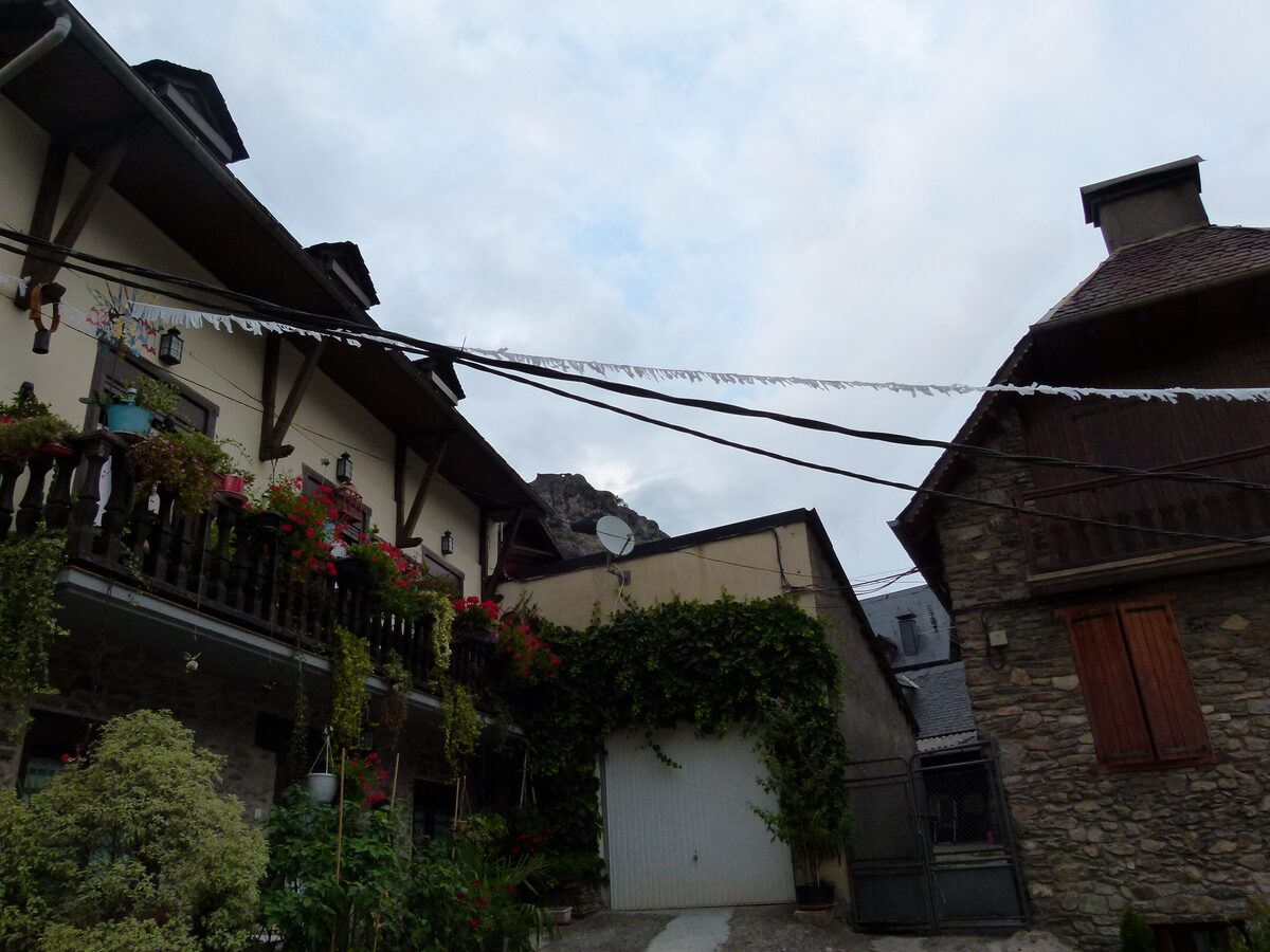 A stone-and-slate street with flower-covered balconies in Bossòst