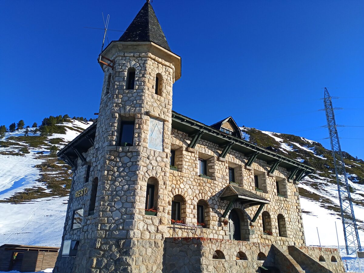 The stone tower of the Cap del Port building at the Bonaigua pass with snow around it