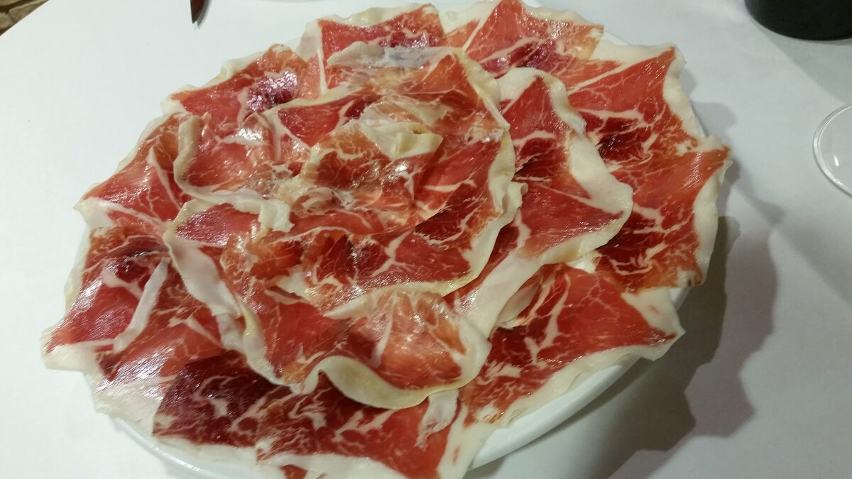 Thin slices of Iberian ham fanned out on a white plate