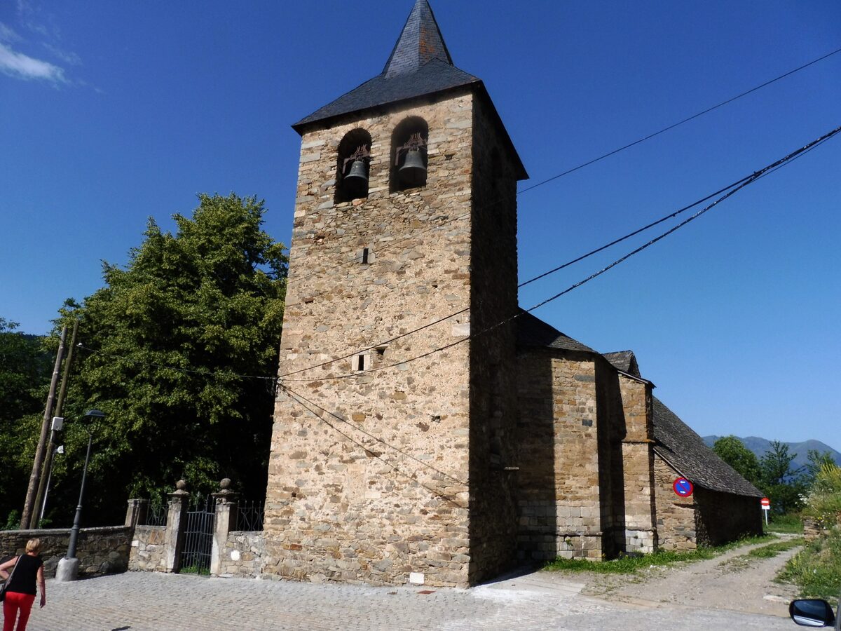 The church of Sant Esteve at Montcorbau, its stone bell tower and nave under a blue sky
