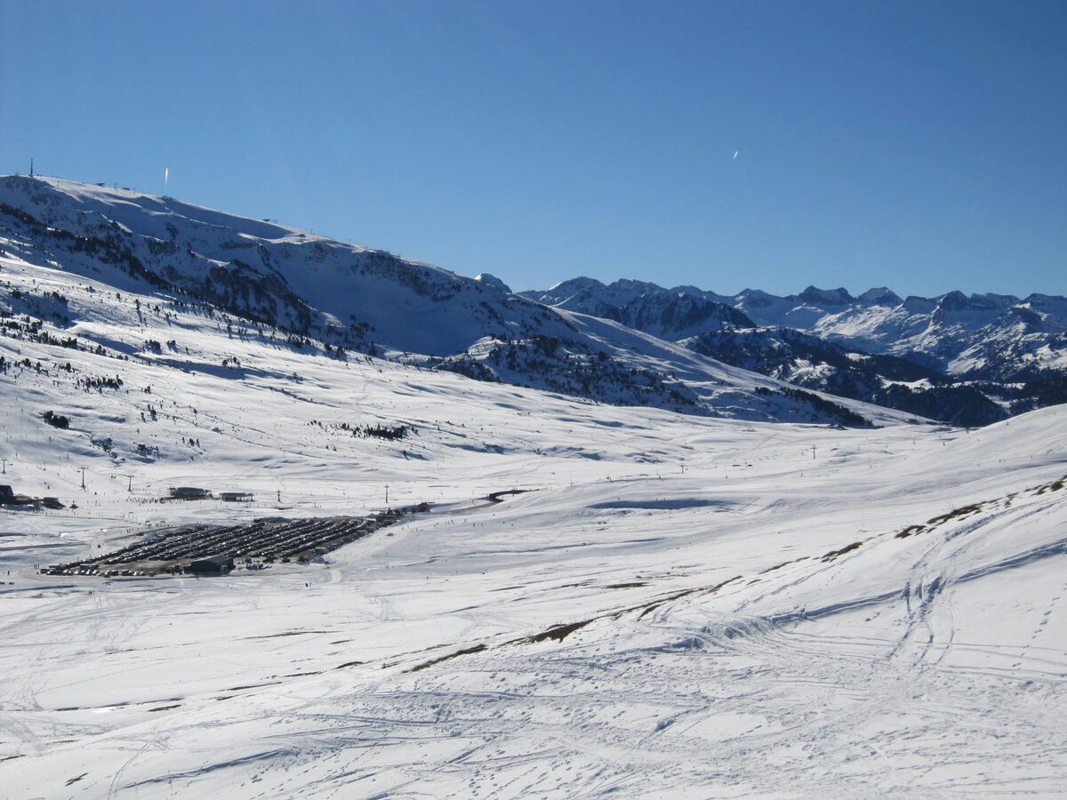 Wide snow-covered slopes and ski tracks on the Pla de Beret plateau under the mountains