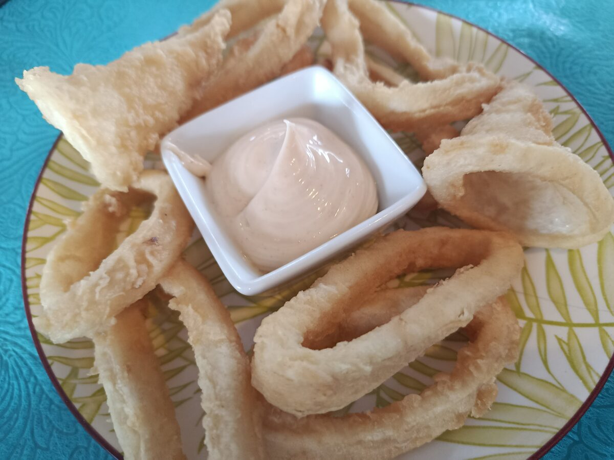 Fried calamari rings with a bowl of aioli on a plate