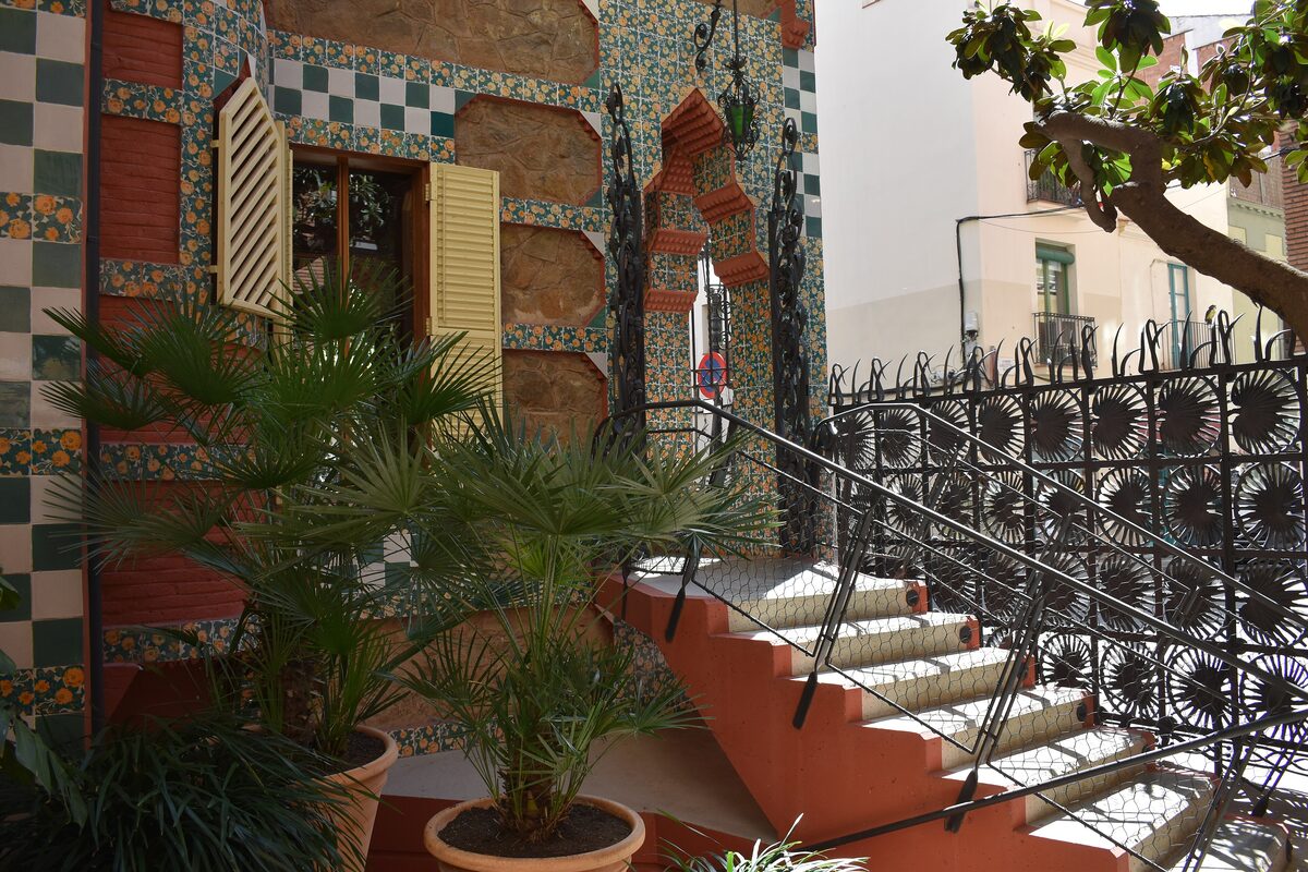 Casa Vicens's green and white tiled facade, with palms and a wrought-iron railing