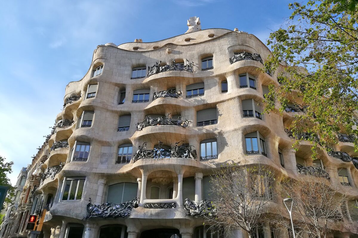 La Pedrera's wavy stone facade and wrought-iron balconies, seen from the corner of Passeig de Gràcia and Carrer de Provença